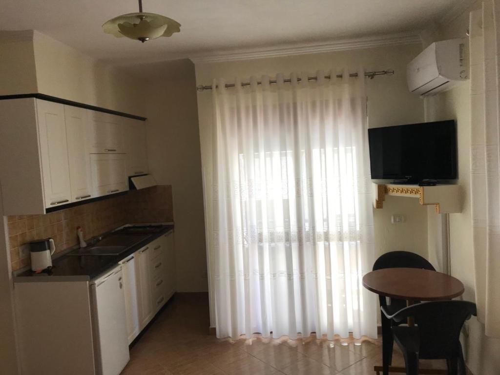 a kitchen with a table and a window with a television at Amras house in Durrës