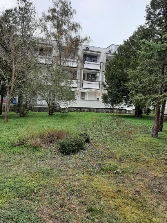 ein Gebäude in einem Park mit Bäumen und Gras in der Unterkunft Clara apartman in Csopak