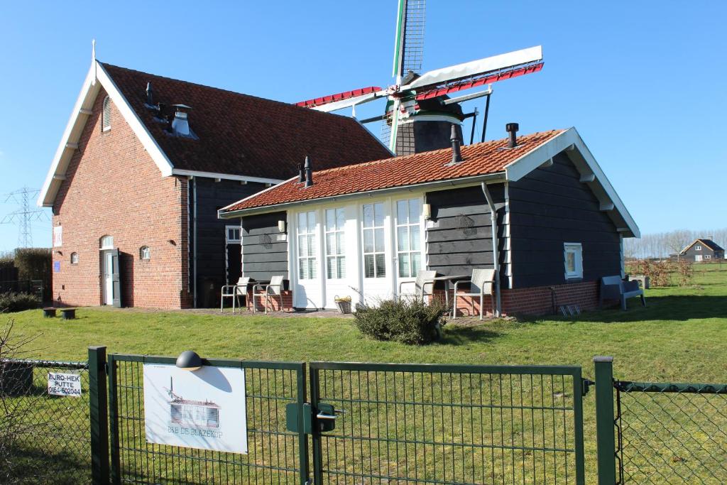 a barn with a windmill in the background at Bij de molen slapen , rustig en landelijk in Ovezande
