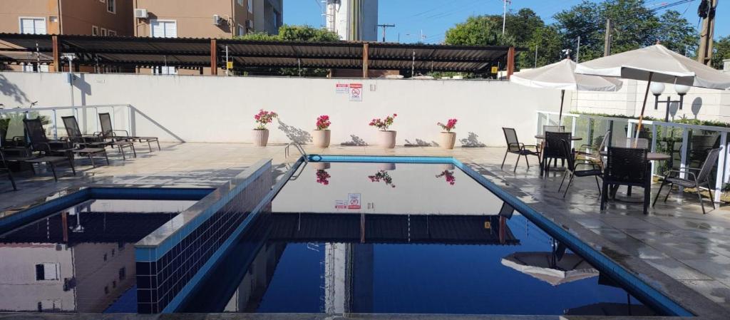 a swimming pool with a table and chairs in it at AP confortável para sua família in Palmas