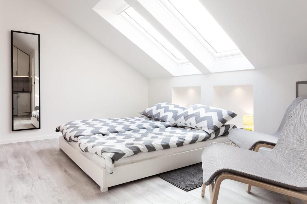 a white bedroom with a bed and a mirror at Studio Chic in Zagreb