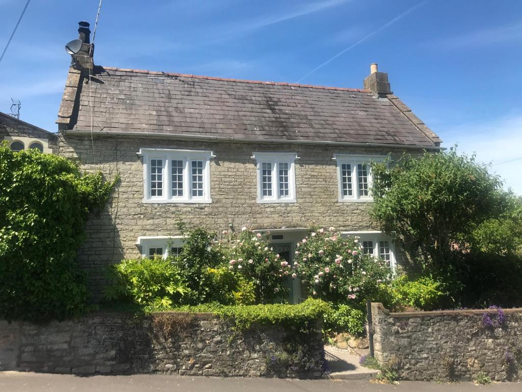 an old brick house with white windows and a stone wall at Quintessential Cottage near Bath, Grade 2 Listed. in Paulton
