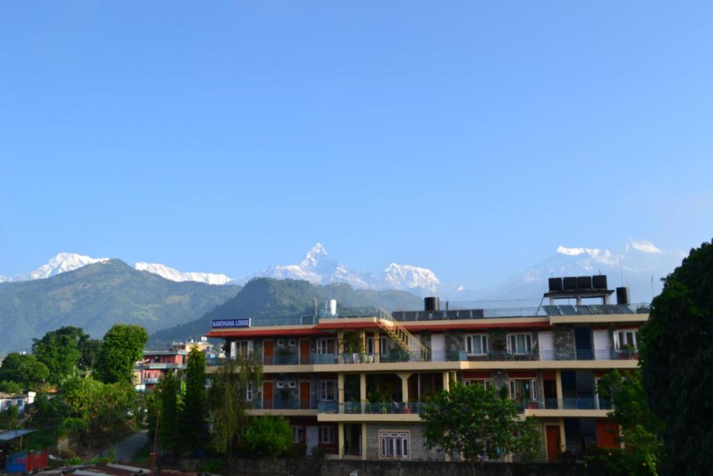 budynek z pokrytymi śniegiem górami w tle w obiekcie Nanohana Lodge w mieście Pokhara