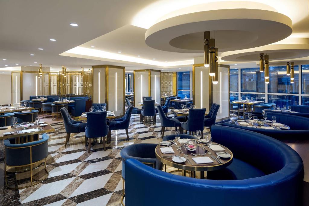 a restaurant with blue chairs and tables and windows at Sheraton Makkah Jabal Al Kaaba Hotel in Mecca