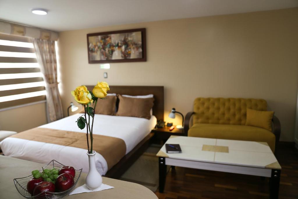a hotel room with two beds and a couch at Hotel Carolina Montecarlo in Quito