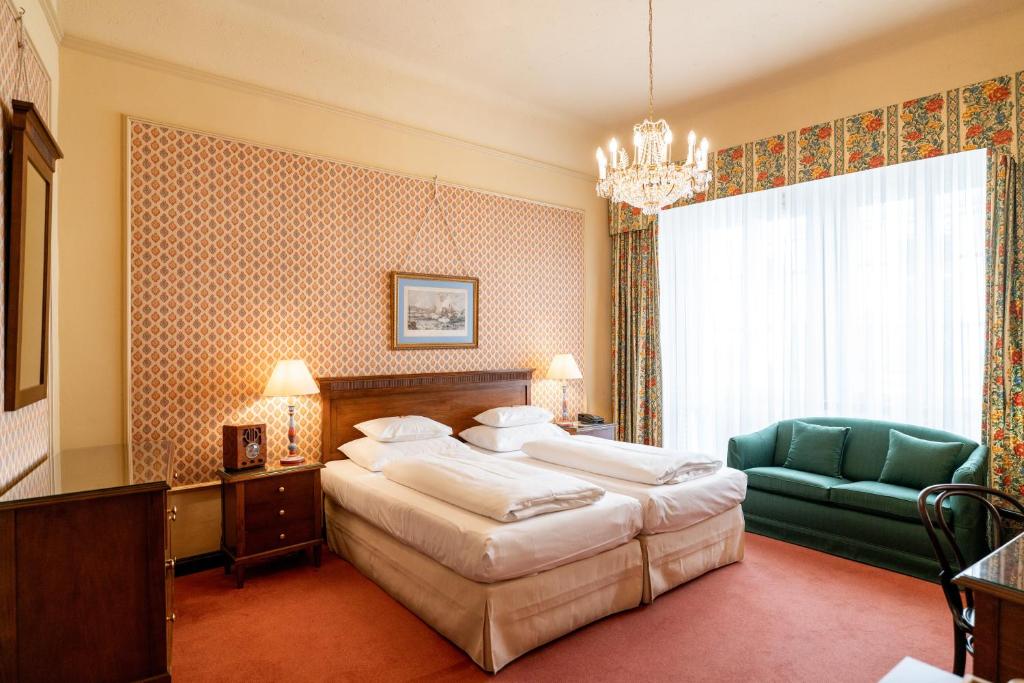 sypialnia z dużym łóżkiem i zielonym krzesłem w obiekcie Hotel König von Ungarn w Wiedniu