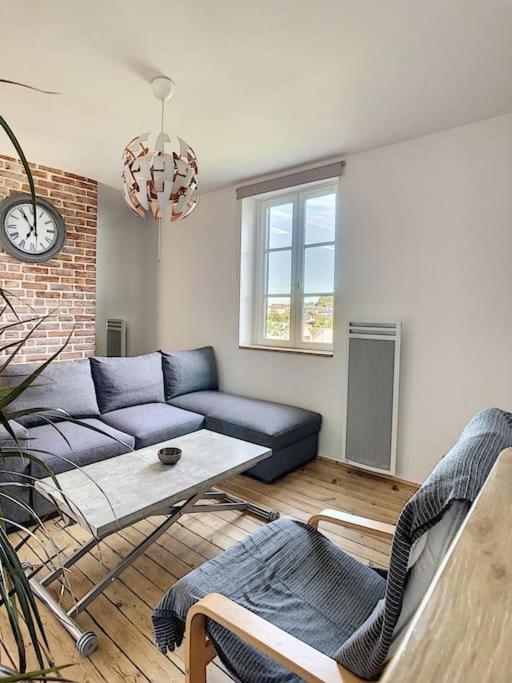 un salon avec un canapé bleu et une table dans l'établissement Les Mouettes. Appart Honfleur 4 personnes vue pont de Normandie, à Honfleur
