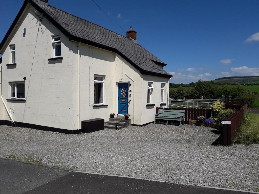 a white building with a blue door and a bench at Mountain View Cottage in Limavady
