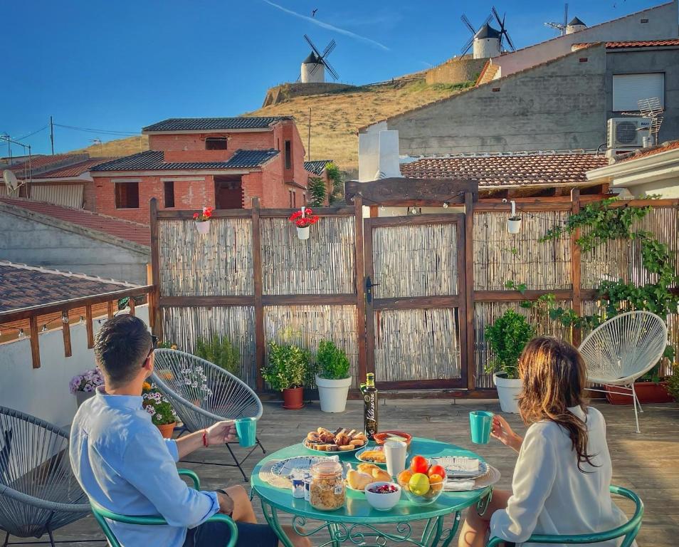a man and a woman sitting at a table with food at Apartamentos Oncemolinos con desayuno in Consuegra