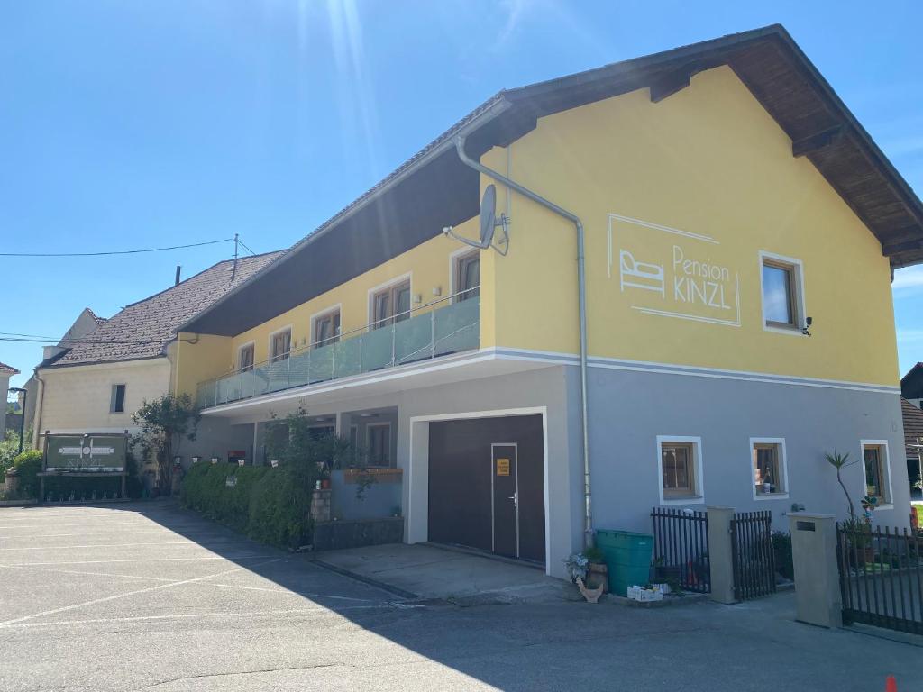 ein gelbes und weißes Gebäude mit einer Garage in der Unterkunft Pension Kinzl in Offenhausen
