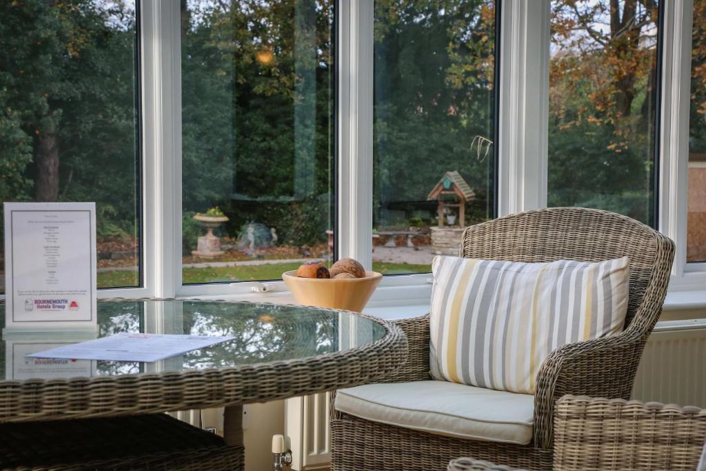 a wicker chair and a glass table in a room with windows at The Grove Hotel in Bournemouth