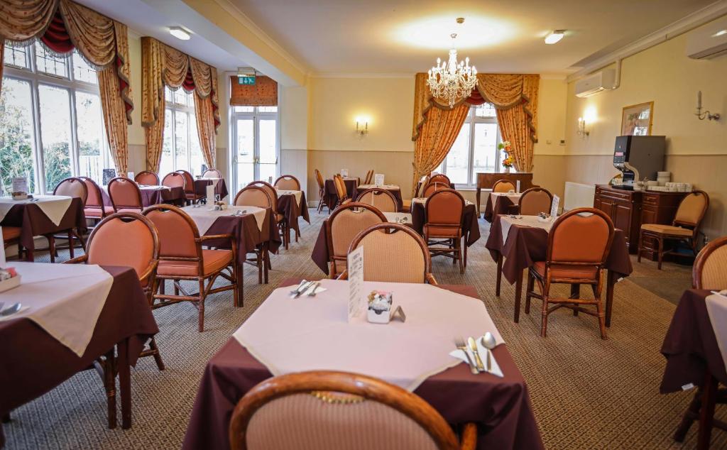 a dining room with tables and chairs and windows at The Grove Hotel in Bournemouth