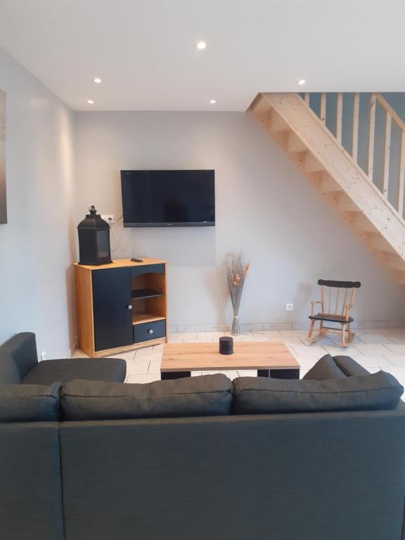 uma sala de estar com um sofá e uma televisão de ecrã plano em Le Rêve de Marcel em Le Molay-Littry