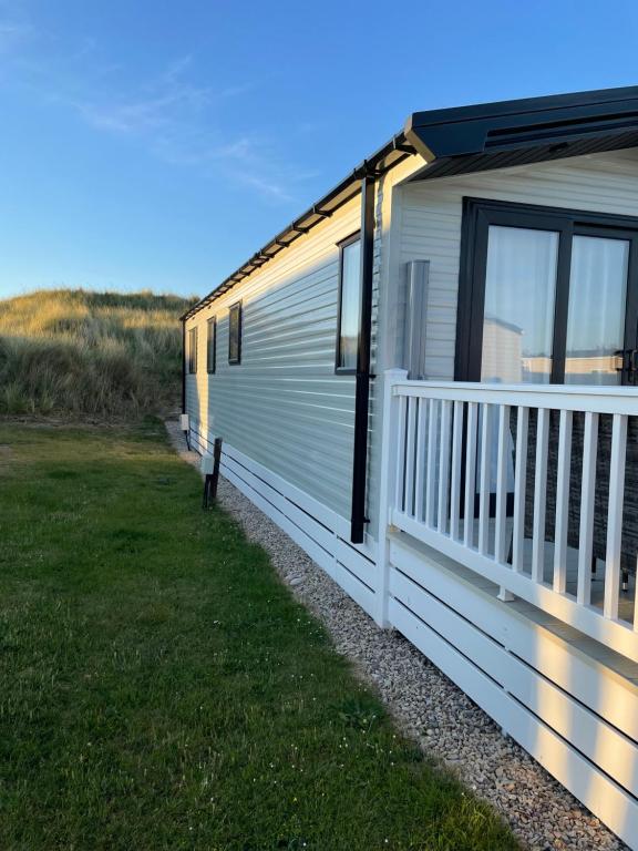 a white mobile home with a porch and windows at Dune View Caravan in Lossiemouth