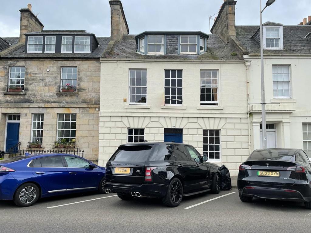 zwei Autos auf einem Parkplatz vor einem Gebäude geparkt in der Unterkunft 4 Bedroom House in the Heart of St Andrews in St Andrews