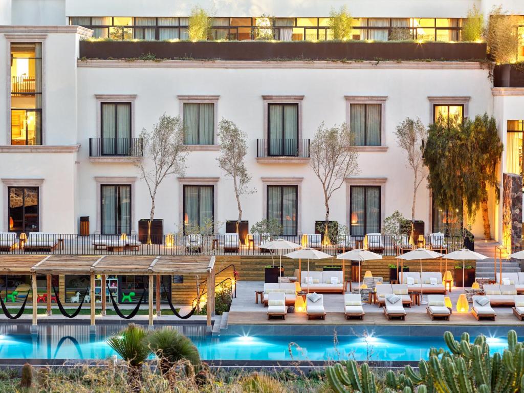 a hotel with a pool and tables and umbrellas at Live Aqua San Miguel de Allende Urban Resort in San Miguel de Allende