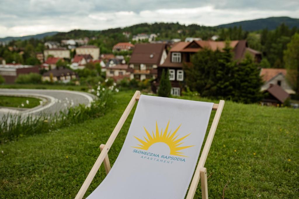 una señal en un campo con un pueblo en el fondo en Apartament Słoneczna Rapsodia, en Rabka