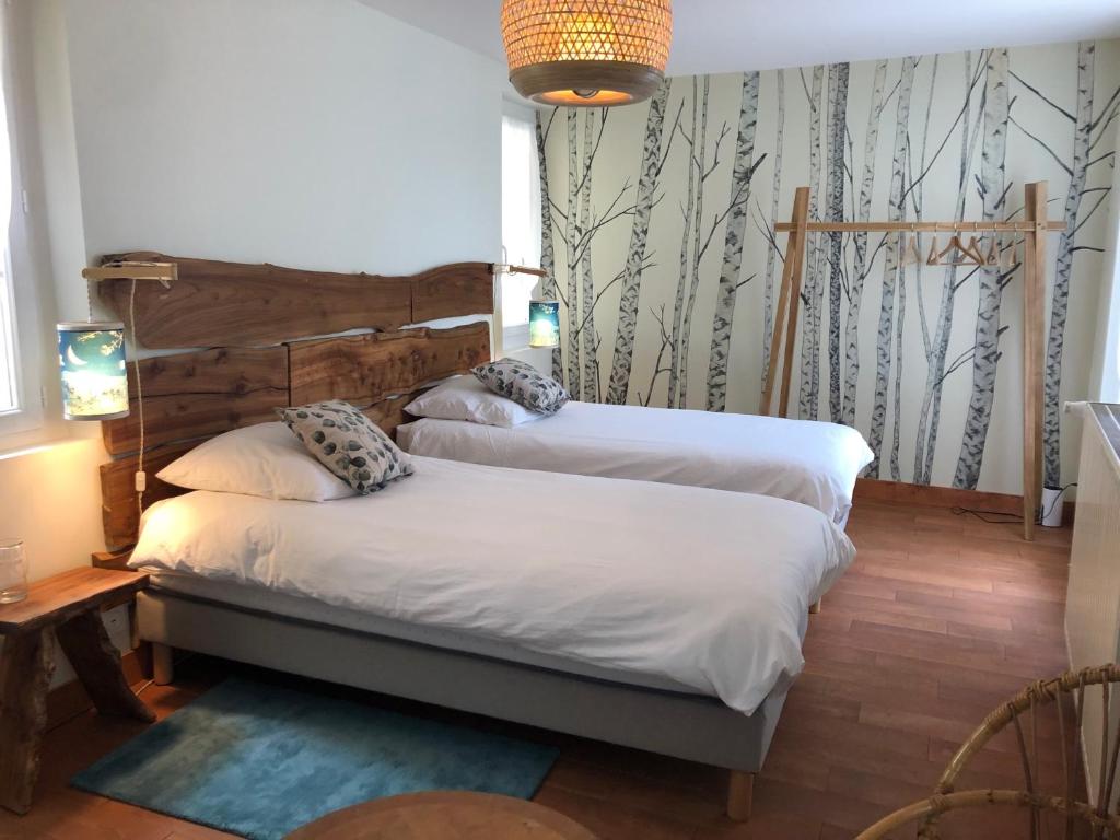 een slaapkamer met 2 bedden en een muur met bomen bij Chambres & Tables d'Hôtes L'Ostal de Pombonne in Bergerac