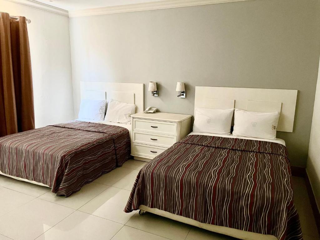 1 dormitorio con 2 camas y vestidor blanco en Hotel Grand Reyes, en Monterrey