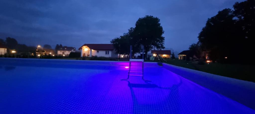 uma piscina com um banco iluminado à noite em Wygodny Dom na Ponidziu z Basenem em Wiślica