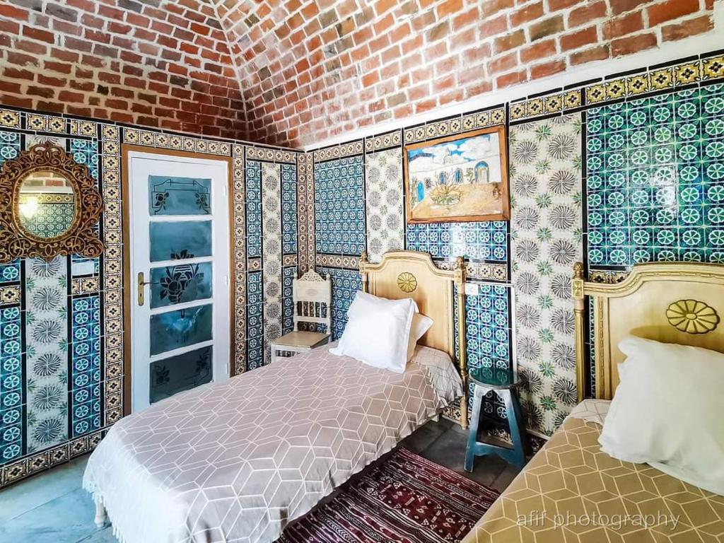 a bedroom with a bed and a brick wall at Hôtel Bou Fares in Sidi Bou Saïd