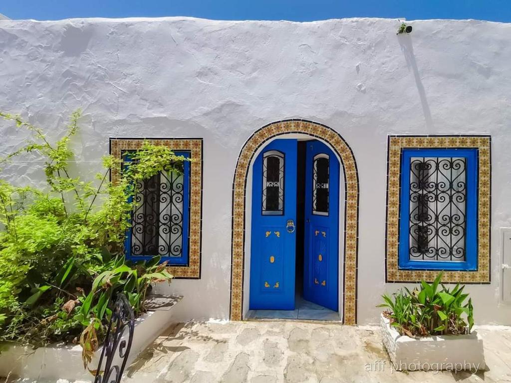 a blue door and two windows on a white building at Hôtel Bou Fares in Sidi Bou Saïd