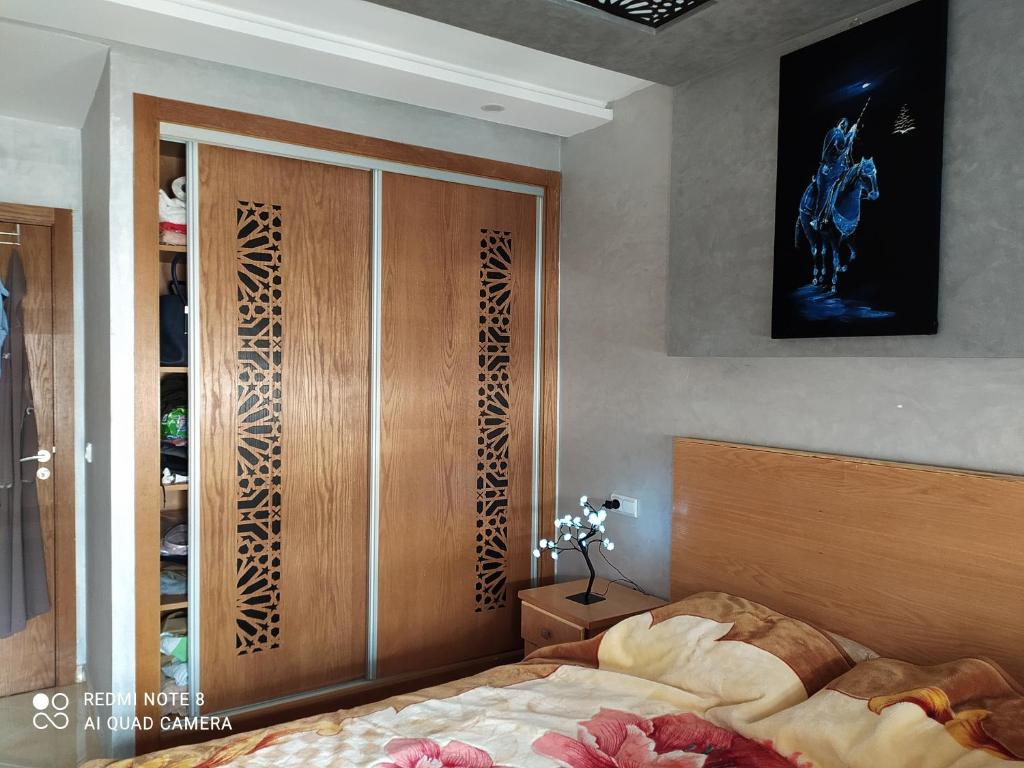 a bedroom with a bed and a wooden closet at Appartement à Bouznika prêt du plage Dahomey, plage bouznika, Bahia beach in Bouznika