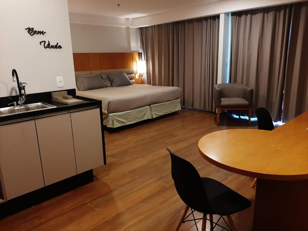 リオデジャネイロにあるBotafogo Suitesのベッドとテーブルが備わるホテルルームです。