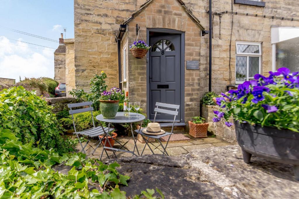 a table and chairs in front of a house with flowers at Cabbage Hall Cottage in Bramham