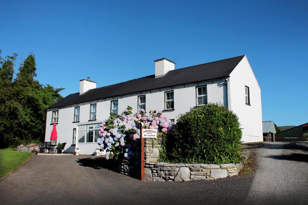 a white house with flowers in front of it at Gortamullen House, Kenmare in Kenmare