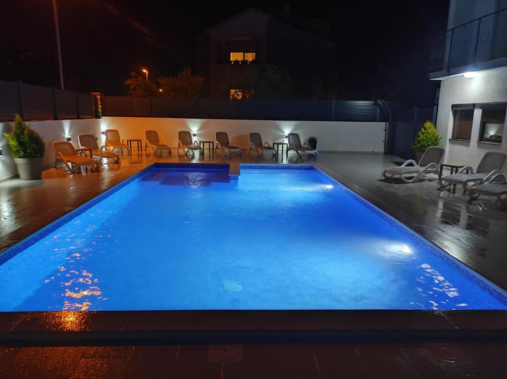 een zwembad 's nachts met tafels en stoelen bij Viktor rooms and apartments in Rovinj