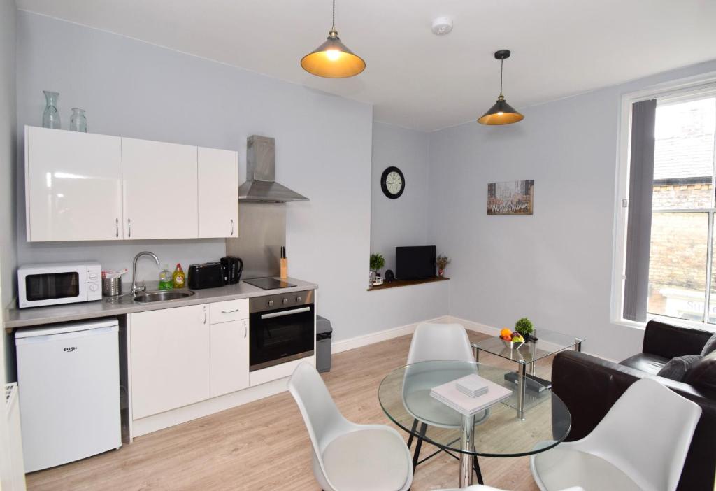 a kitchen and living room with white cabinets and a table at Malton Central Apartments in Malton