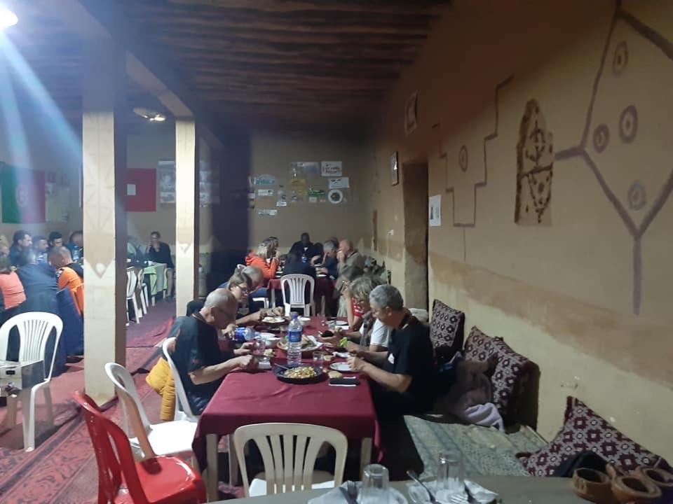 grupa ludzi siedzących przy stole w restauracji w obiekcie Auberge Dinosaur Kem Kem w mieście Tafraoute Sidi Ali