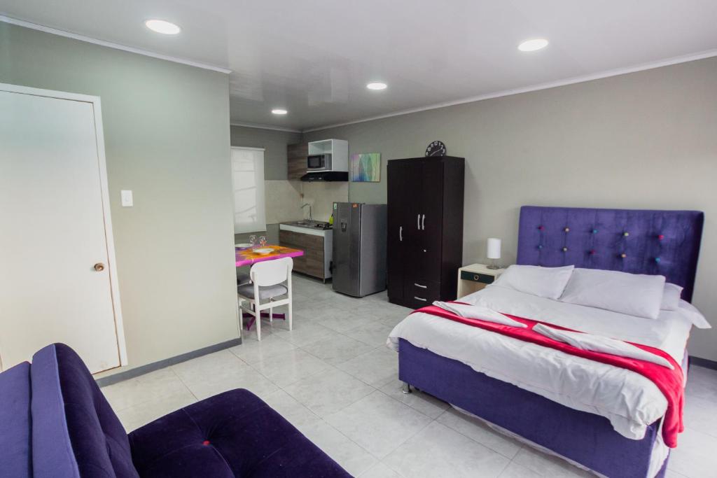 a bedroom with a blue bed and a kitchen at ApartaSuites & Hotel Bogota Teusaquillo in Bogotá