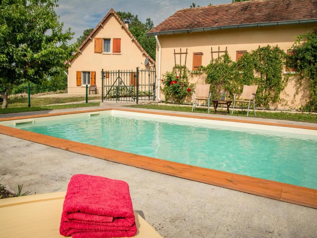 a swimming pool with a towel on a table next to a house at Gite LEysalle in Ribagnac