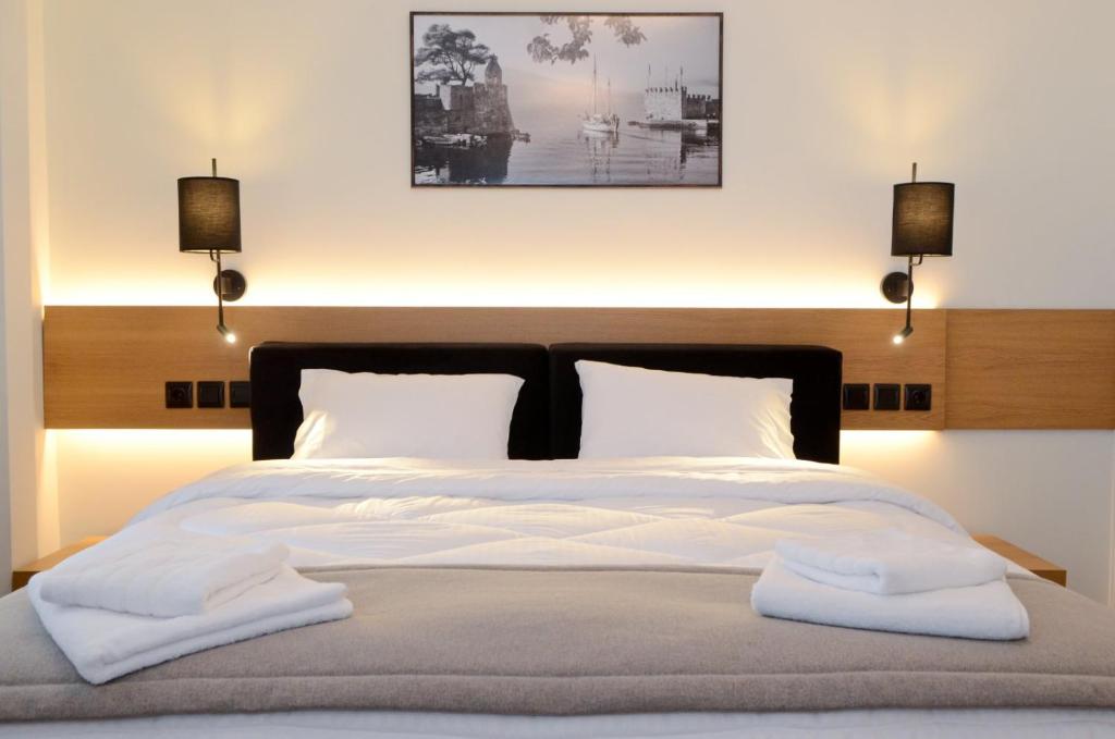 a bedroom with a large bed with two lights at Roloi suites in Nafpaktos