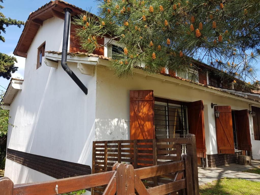 una pequeña casa blanca con una valla de madera delante de ella en Valerianas en Valeria del Mar