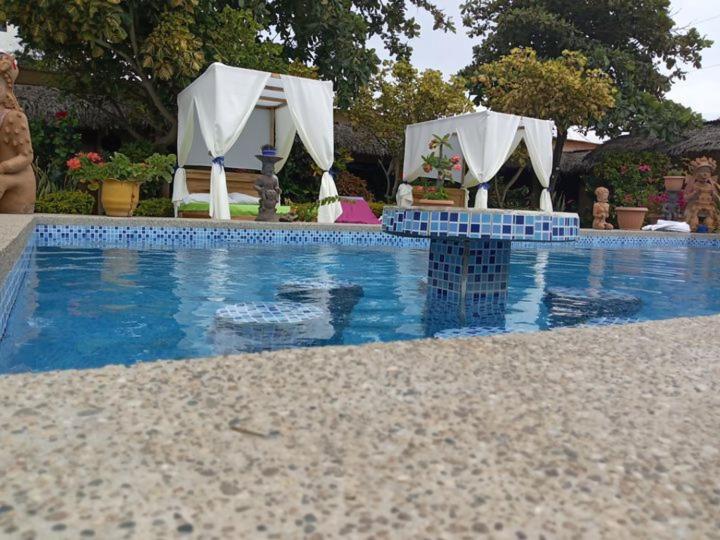 una piscina con sombrillas azules y blancas en un patio en The Cottages by the Sea en San Clemente