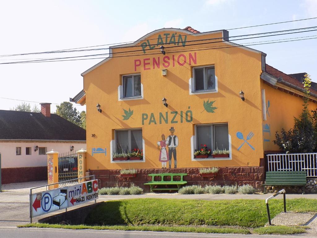 a yellow building with a painting on the side of it at Platán Panzió in Nyúl
