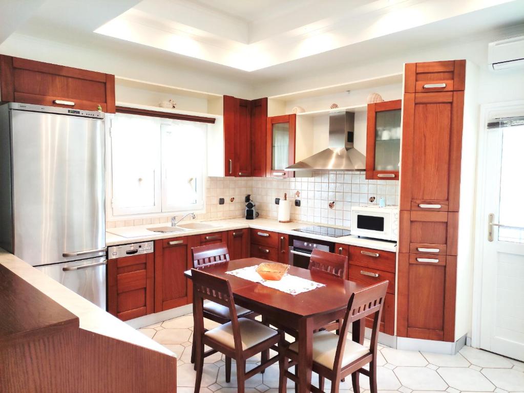 - une cuisine avec des placards en bois, une table et des chaises dans l'établissement Anastasiou Home in central crossroad, à Perdika