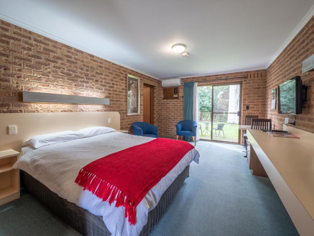 a bedroom with a bed with a red blanket at Eildon Parkview Motor Inn Room 1 in Eildon