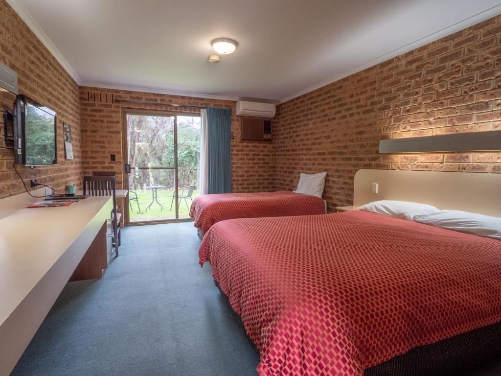 sypialnia z 2 łóżkami i ceglaną ścianą w obiekcie Eildon Parkview Motor Inn Room 2 w mieście Eildon