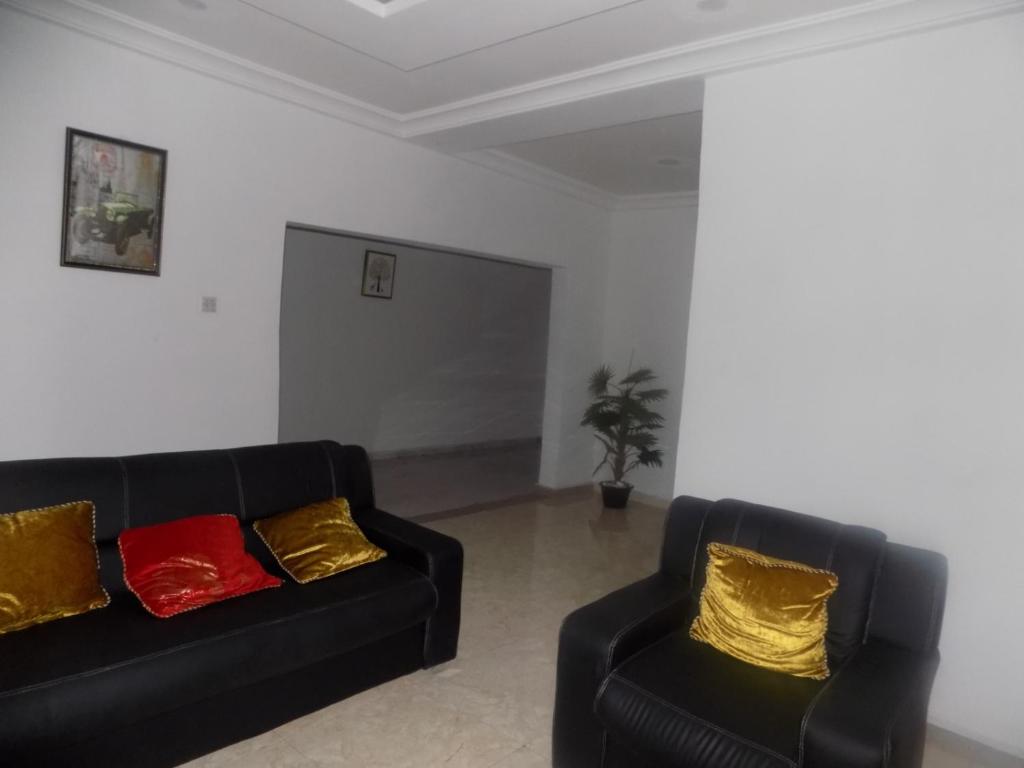 2 sofás negros con almohadas rojas y amarillas en la sala de estar en Great Secured 1Bedroom Service Apartment ShortLet-FREE WIFI - Peter Odili RD - N29,000, en Port Harcourt