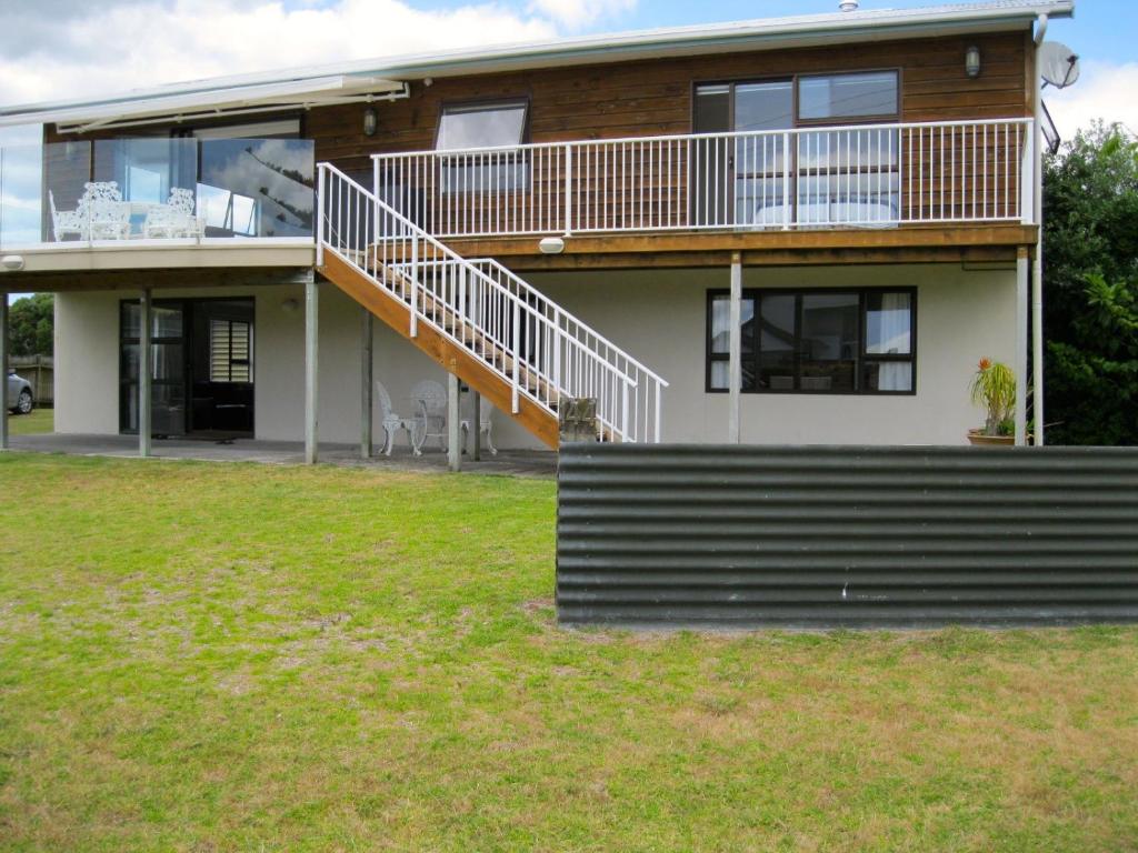 a large house with a balcony and a yard at Cooks Beach Gem - Cooks Beach Holiday Home in Cooks Beach