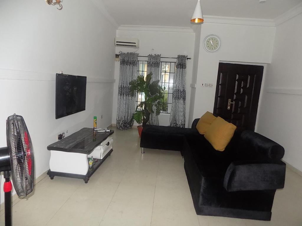 a living room with a black couch and a table at Unique 1BEDROOM Shortlet Stadium Rd with 24hrs light-FREE WIFI -N35,000 in Port Harcourt