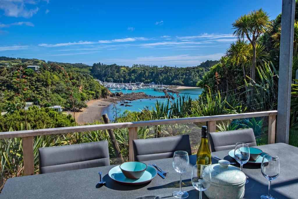 a table with wine glasses and a view of a river at Marina Views - Tutukaka Holiday Home in Tutukaka
