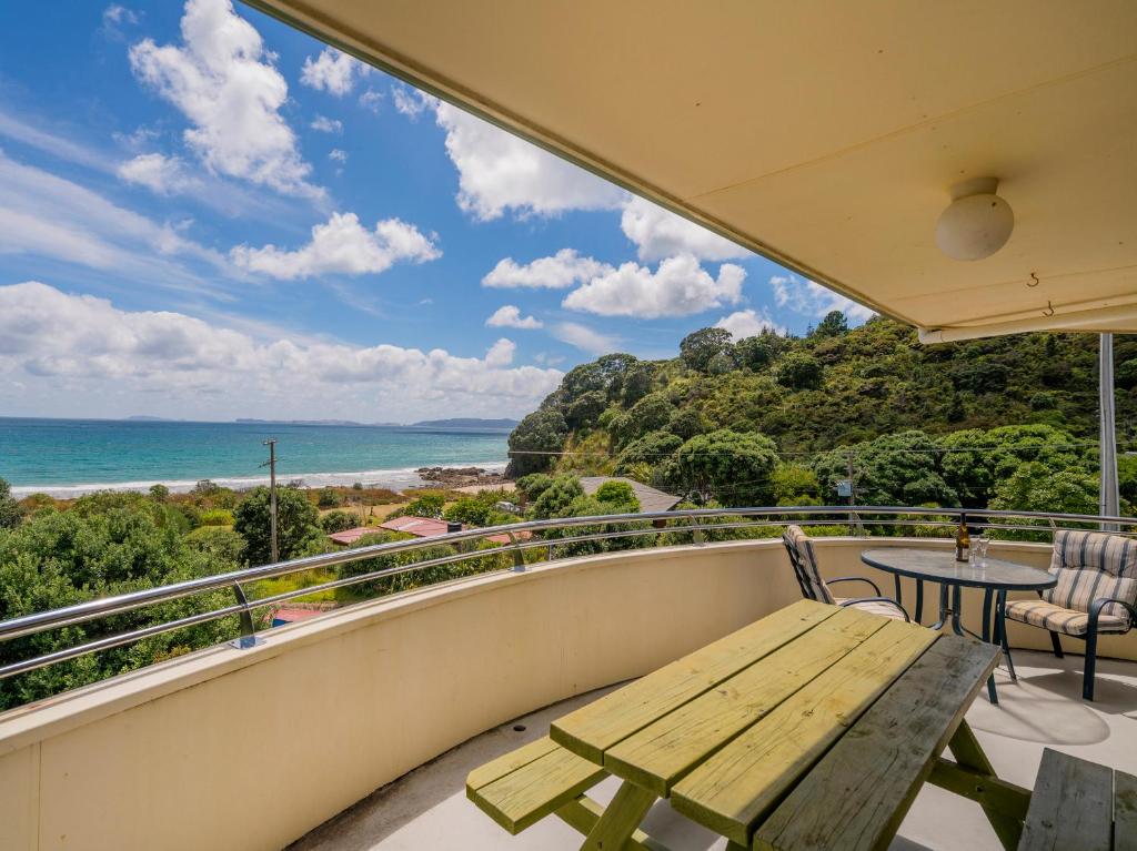 d'un balcon avec un banc en bois et une vue sur l'océan. dans l'établissement Easties Manner - Rings Beach Holiday Home, à Matarangi