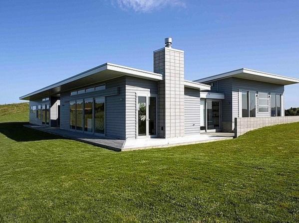 een klein huis op een heuvel met een groen veld bij The Perfect Degree - Sandy Bay Holiday Home in Matapouri