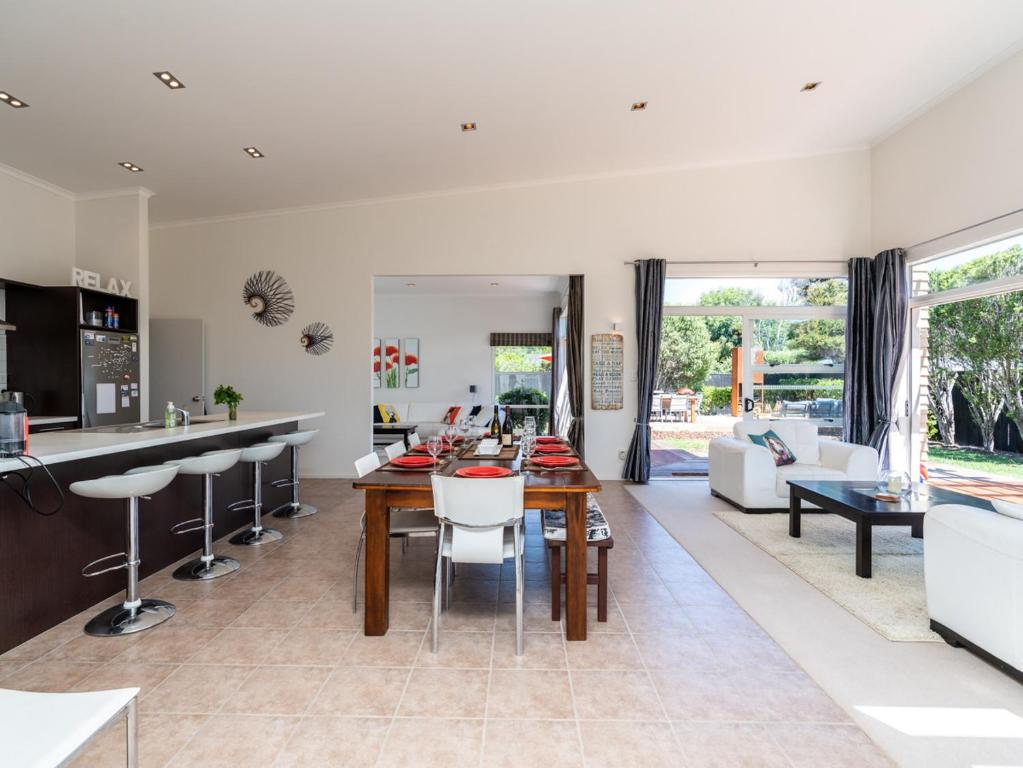 a kitchen and living room with a table and chairs at Magnifique - Mangawhai Holiday Home in Mangawhai
