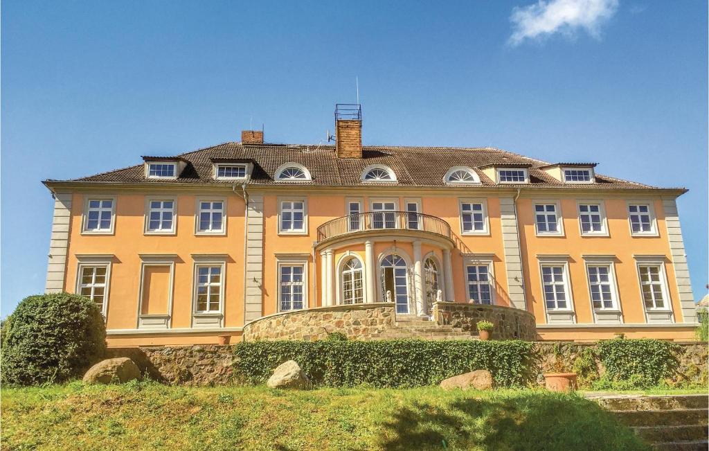 a large yellow house on a grassy hill at Herrenhaus Lbbenow in Uckerland